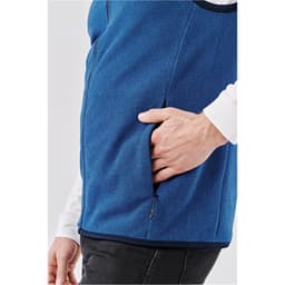 A blue vest featuring a side pocket, worn over a white long-sleeve shirt. It has a sleek design and casual style.