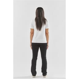 A woman wearing a white women's Ferrera polo shirt, viewed from the back, paired with black pants.