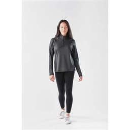 A long sleeve, quarter-zip jumper in dark grey, paired with black leggings and white sneakers, featuring a logo.