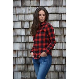 A women's red and black checkered button-up shirt with a snap front, worn by a model against a wooden background.