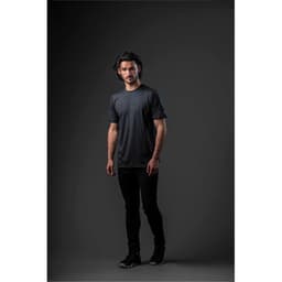 A model wearing a black short-sleeve t-shirt, standing against a dark background. The shirt has a logo.