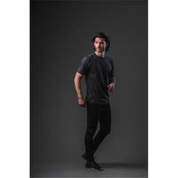 A model wearing a short-sleeve men's T-shirt in dark grey, standing against a black background. The shirt features a logo.