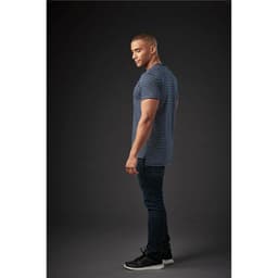 A man wearing a navy and white striped crew neck t-shirt, paired with dark jeans and black sneakers.