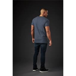 A man wearing a navy and white striped crew neck tee, paired with dark jeans, viewed from the back against a dark background.