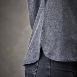 A grey women's polo shirt featuring side slits and a classic design, showcasing textured fabric.