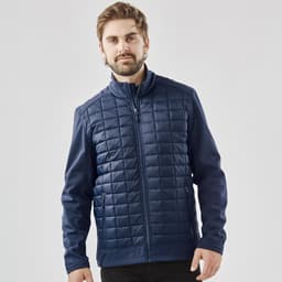 A men's navy softshell jacket with a quilted front and a straight zip closure, featuring a logo on the chest.