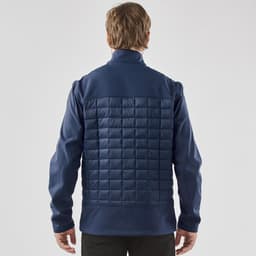 A navy blue men's softshell jacket with a quilted back and raised collar, featuring a logo on the upper left.