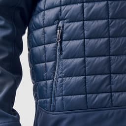 A navy thermal softshell jacket featuring a quilted texture and a zippered pocket on the side.
