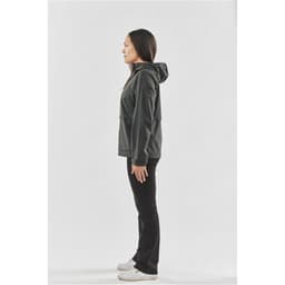 A woman wearing a black rain jacket with a hood, standing in profile against a plain background.