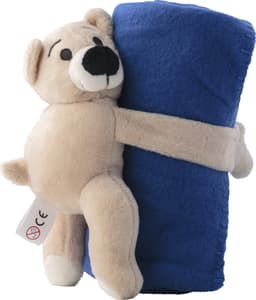 A plush toy bear in a light brown colour, holding a blue fleece blanket. The bear has a friendly expression.