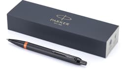 A black Parker IM Vibrant Rings PVD ballpoint pen with an orange accent, displayed alongside its branded box.