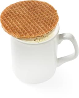 A golden-brown Dutch waffle rests on the rim of a white mug filled with a warm beverage.