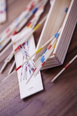 A wooden Mikado game featuring colourful sticks scattered on a wooden surface, with a storage box visible.