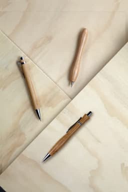 Bamboo ballpens in various designs on a wooden surface, featuring natural bamboo shades and metallic accents.