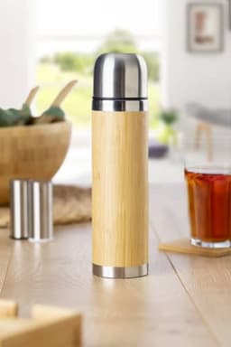 A drink bottle made of bamboo with a stainless steel cap, standing on a wooden table.
