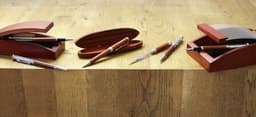 A rosewood writing set featuring pens and letter openers in elegant red cases on a wooden surface.