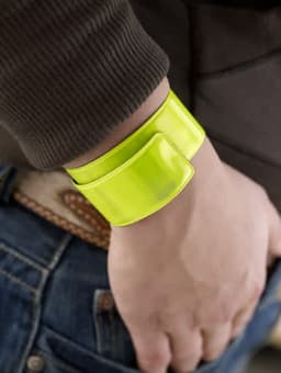 A vibrant yellow PVC arm band worn on a wrist, showcasing its glossy finish and sleek design.