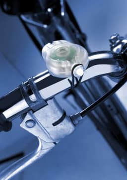 A clear ABS bicycle light attached to a bike handlebar with a metallic grip, set against a blue background.