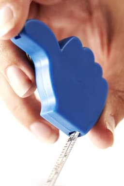 A blue key holder shaped like a hand, holding a retractable measuring tape.