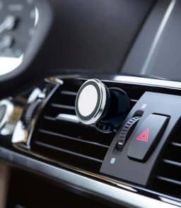 A black and silver ABS smartphone holder attached to a car air vent, designed for secure mobile device placement.