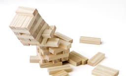 A wooden skills game featuring light-coloured blocks stacked and scattered on a white background.