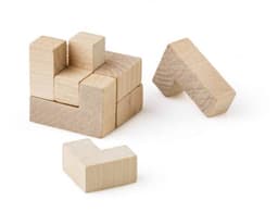 A wooden cube puzzle consisting of light-coloured wooden blocks, some assembled and others separate, on a white background.