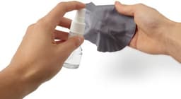A clear spray bottle with a white nozzle and a grey cleaning cloth held in hands.