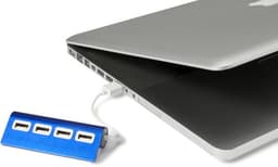 A blue aluminium USB hub connected to a laptop, featuring four USB ports. The laptop is slightly open.