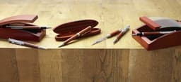 A set of elegant rosewood ball pens displayed with matching boxes on a wooden surface.