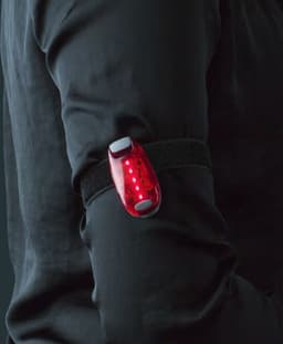 A red ABS safety light attached to a black armband, positioned on a person's upper arm.