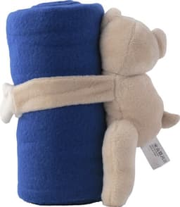 A beige plush bear cuddles a rolled blue fleece blanket. The bear features a simple design and has a small tag.