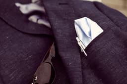 A metal Parker Jotter ballpen in silver, placed alongside a light blue pocket square in a suit jacket pocket.