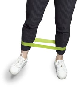 A set of three elastic sports bands in green, secured around the legs, worn by a person in patterned trousers and white sneakers.