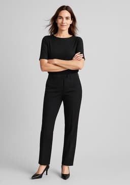 A woman wears black comfort wool stretch relaxed pants paired with a black top and high heels, standing confidently.