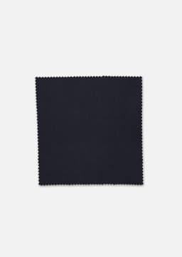 A square swatch of black fabric with a textured finish, edged with a zigzag pattern.
