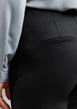 A close-up of black women's leggings, featuring a back pocket and part of a light blue top.