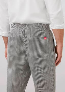 A pair of mens track pants in a black and white checkered pattern, featuring a waistband and pockets on the back.