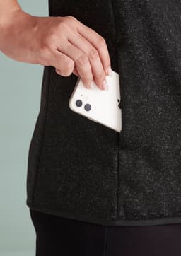 A black jumpers with a side pocket, showing a hand placing a phone inside. Features a sleek design and soft fabric.