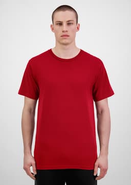 A man stands wearing a red short sleeve t-shirt. The t-shirt has a simple design and features a logo.