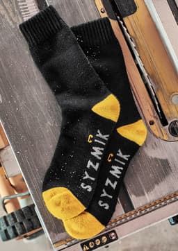A pair of black and yellow work socks with branding, displayed on a wooden surface.
