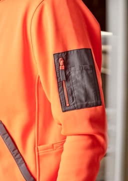 An orange unisex water-resistant hoodie features a contrast black zippered pocket on the sleeve and has a logo.