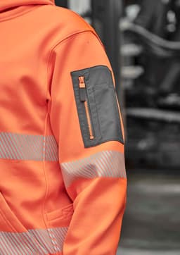 A vibrant orange water-resistant hoodie featuring segmented grey tape and a zippered pocket on the arm.