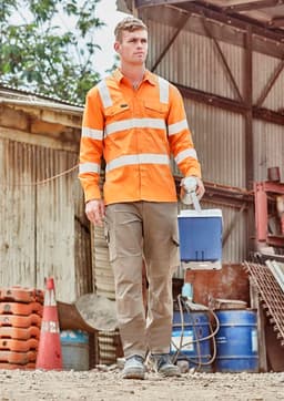 A man wears an orange long sleeve work shirt with reflective stripes, carrying a blue cooler in an outdoor setting.