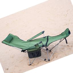 A green camping lounge chair with adjustable armrests and a headrest, resting on sandy ground.