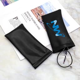 A black PU eyeglass pouch with a logo, placed on a surface alongside a pair of glasses and a magazine.