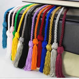 A collection of graduation honour cords in various colours, featuring twisted designs and tassels, displayed over a book.