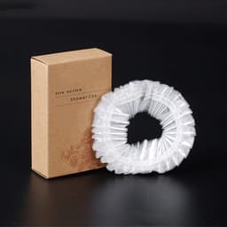 A clear disposable shower cap packaged in a brown cardboard box, featuring a logo.