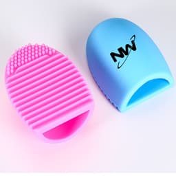 A silicone makeup brush cleaner in pink and blue, featuring text branding on one side and textured surfaces for cleaning.