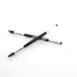 A double-headed eyebrow brush with a black handle and clear packaging, featuring a spoolie and angled brush.