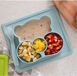A non-slip children's plate in a bear shape, featuring sections for food in light blue. Includes a spoon.